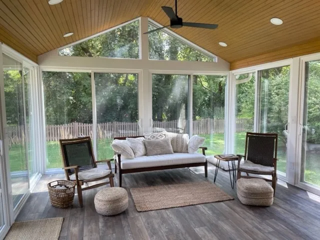All-season sunroom with a wood cathedral ceiling, a fan and sliding glass walls looking onto the yard