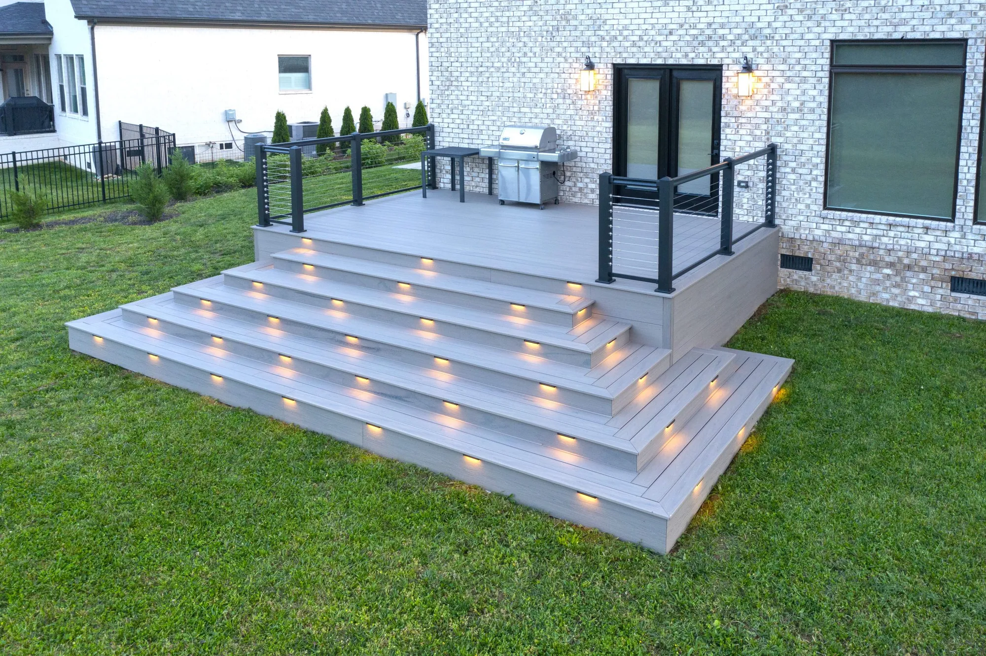 Wide gray composite deck steps with lights set into each riser