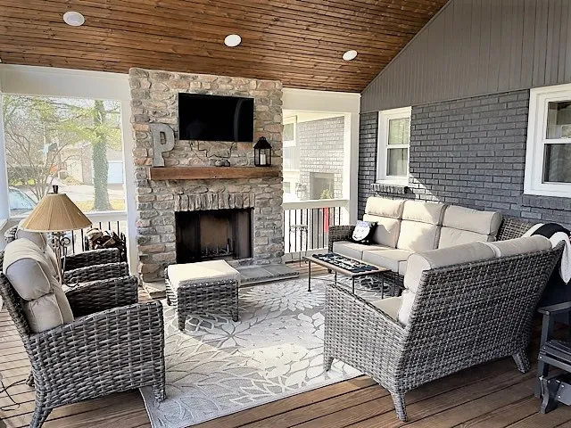 Screen room with a stone fireplace, a television, a wood ceiling and wicker chairs