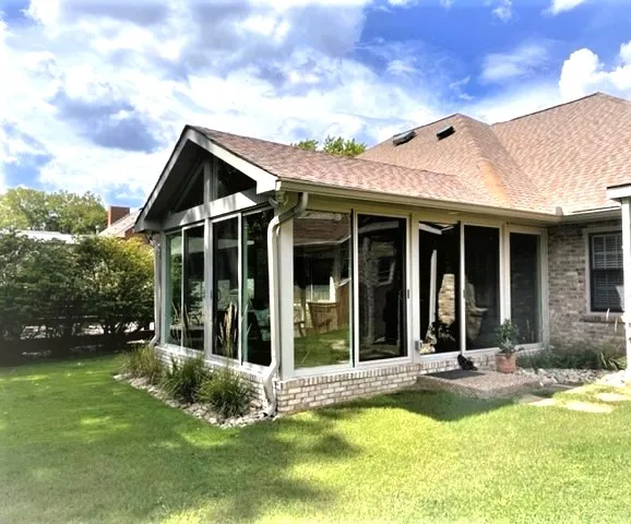 Gable all-season sunroom with full glass walls on the back of a brick ranch on Pebble Glen