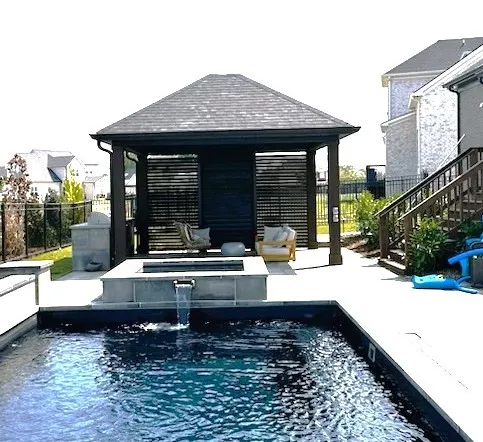 Hip-roof pavilion with dark slatted privacy walls beside a small pool and spa