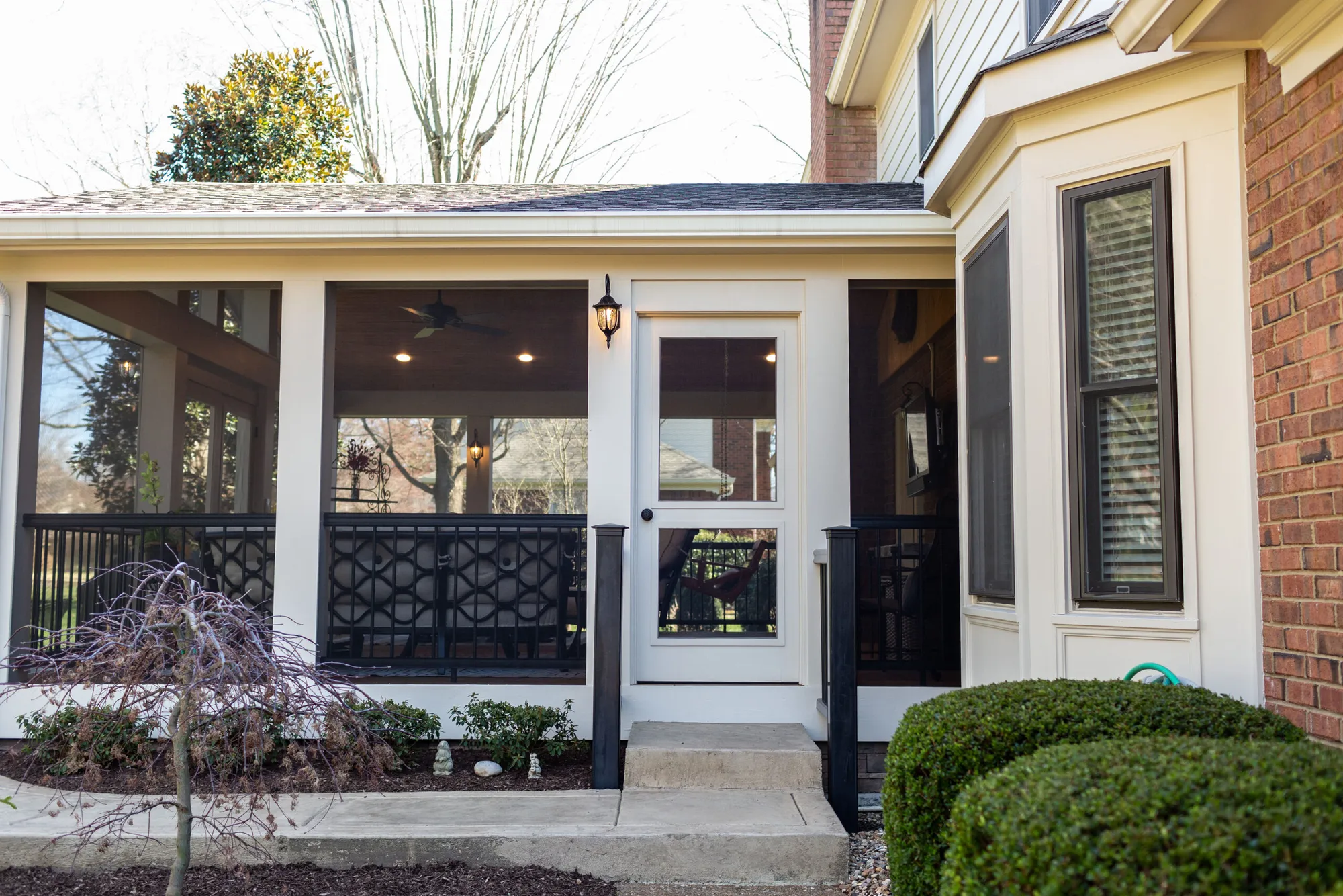 Screen room with black trim and a door to the yard beside a brick chimney on Brushboro