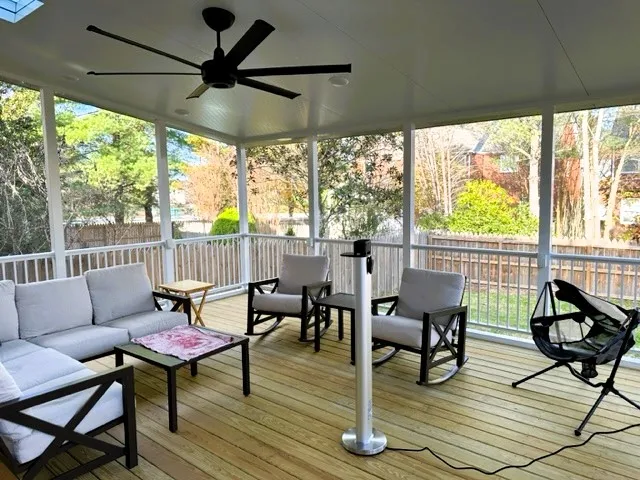 White aluminum screen room with a ceiling fan, outdoor sofas and a patio heater